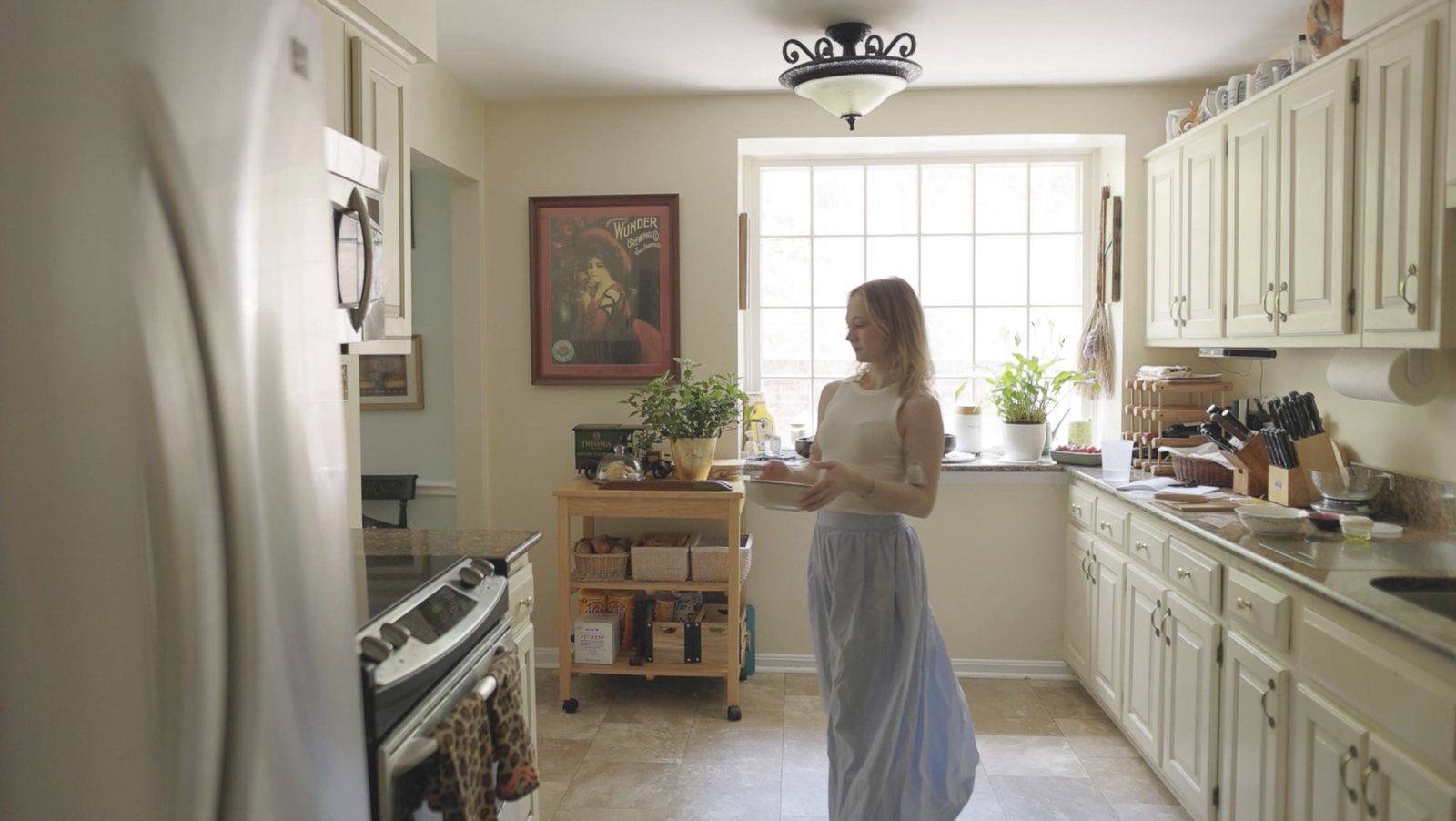 A baker standing at the counter of a bright home kitchen.