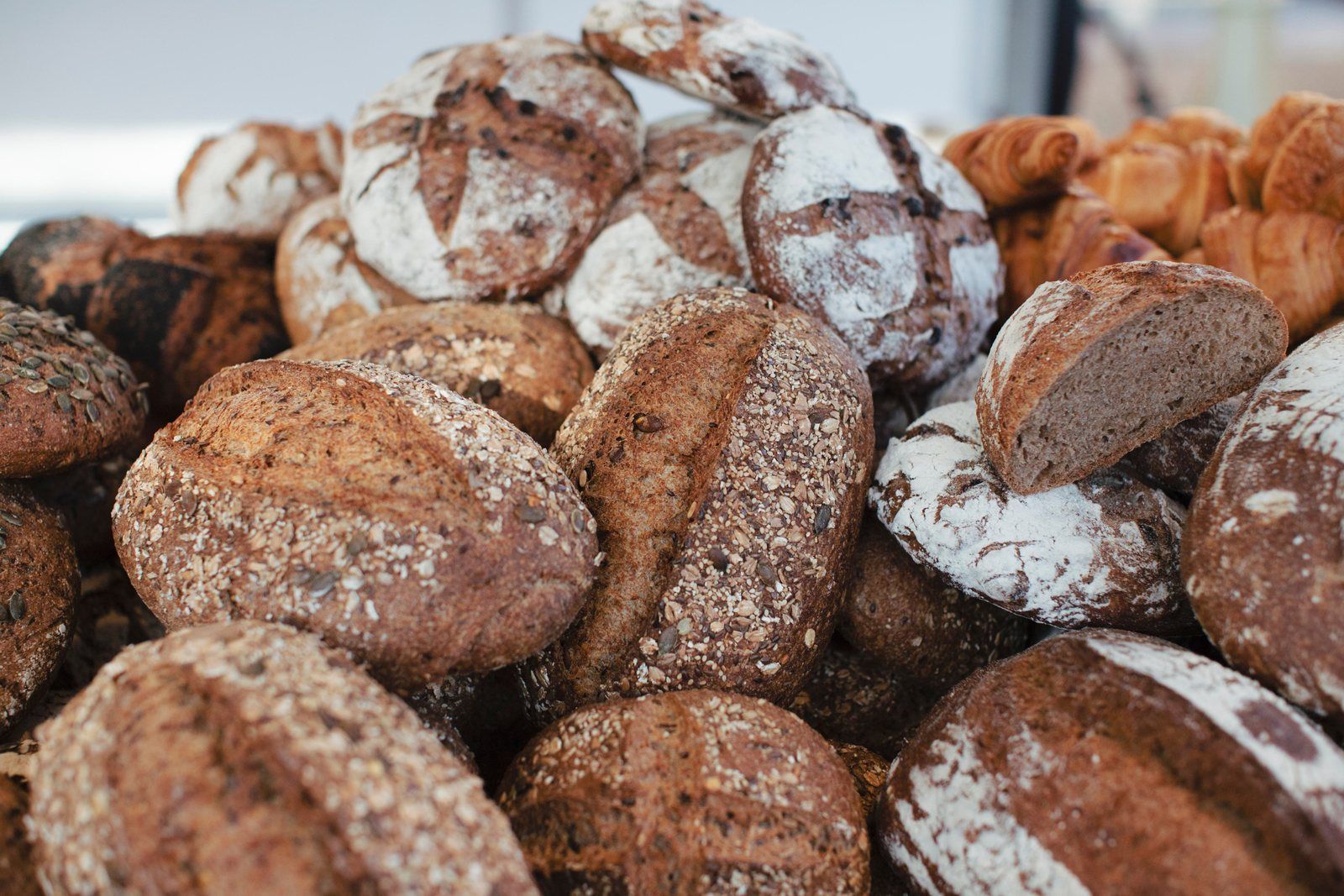 Rustic sourdough loaves and croissants piled on a bakery counter.